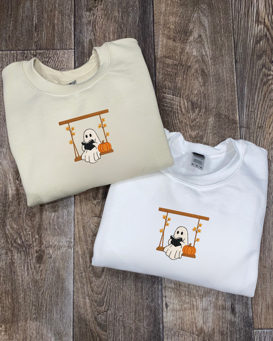 Two folded sweatshirts with Halloween-themed designs on a wooden surface