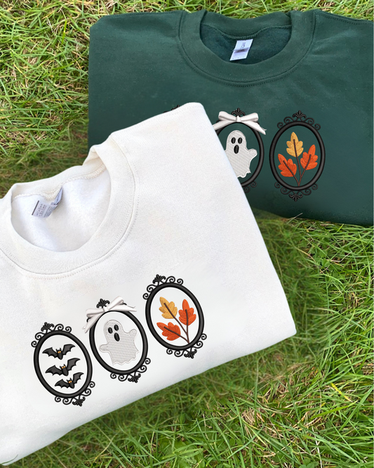 Two sweatshirts with Halloween-themed embroidered designs on a grassy surface